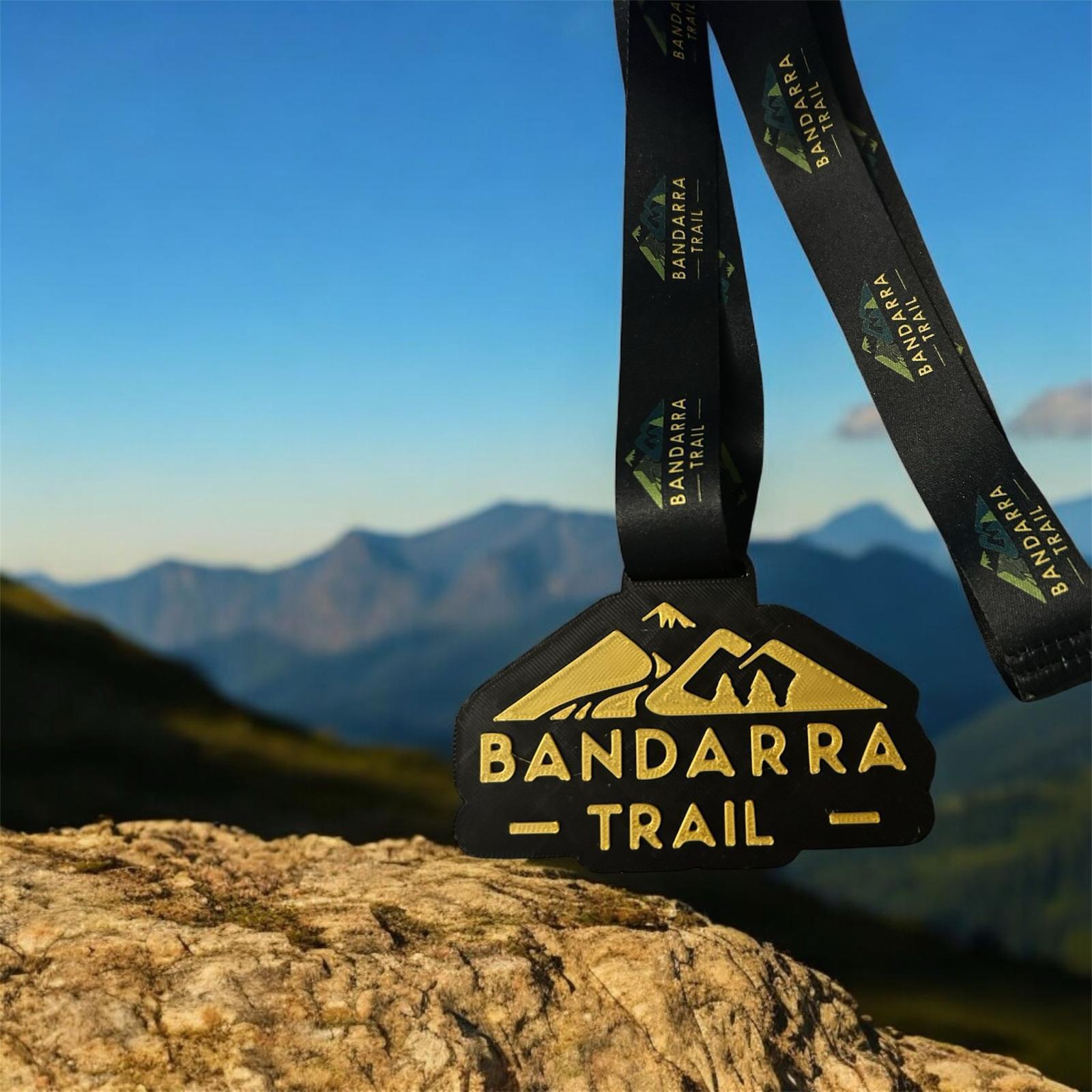 Medalla personalizada en impresión 3D para la competición Bandarra Trail con montañas de fondo.
