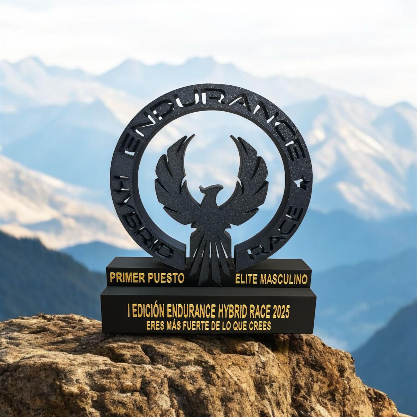 trofeo-primer-puesto-elite-masculino-endurance-hybrid-race Trofeo negro y dorado de primer puesto Elite Masculino para la Endurance Hybrid Race expuesto sobre una roca con montañas de fondo.